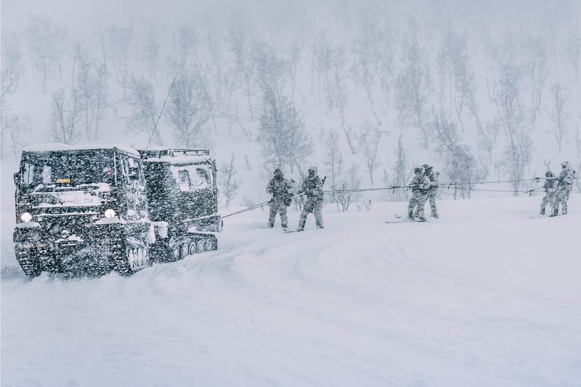 Een BV206 sleept Nederlandse mariniers op ski's (het zogenoemde skijoring) door een besneeuwd landschap in Noorwegen.