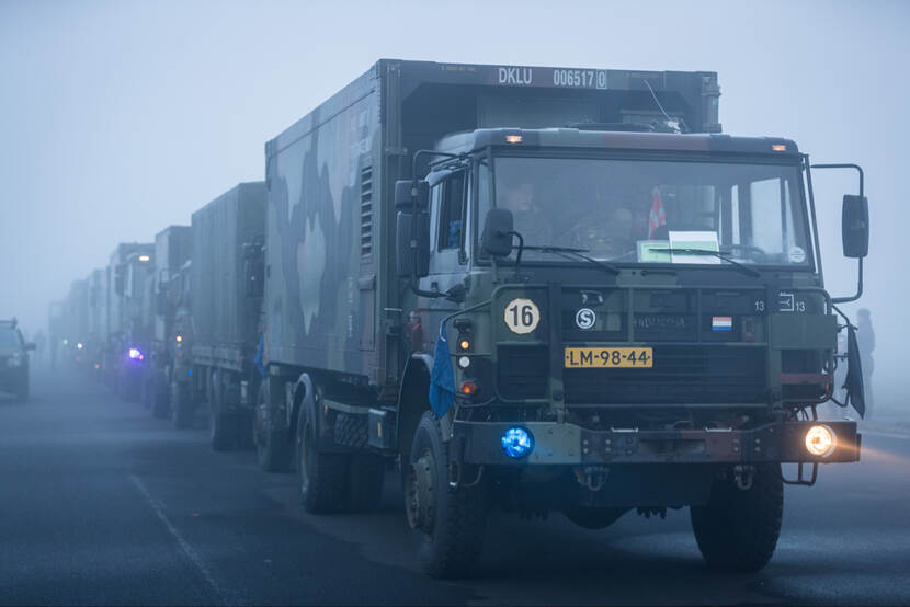 Rij militaire vrachtwagens in de mist.