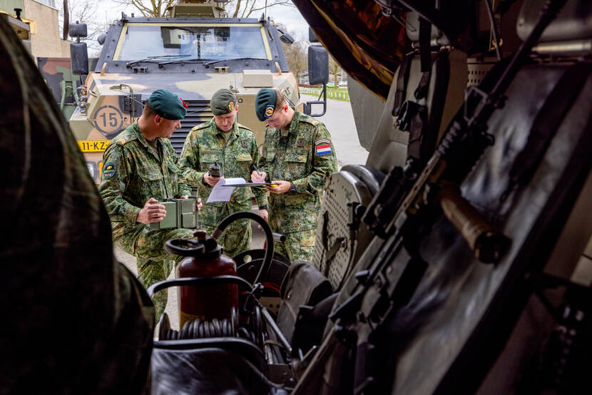 3 landmachtmilitairen controleren de technische staat van een voertuig.