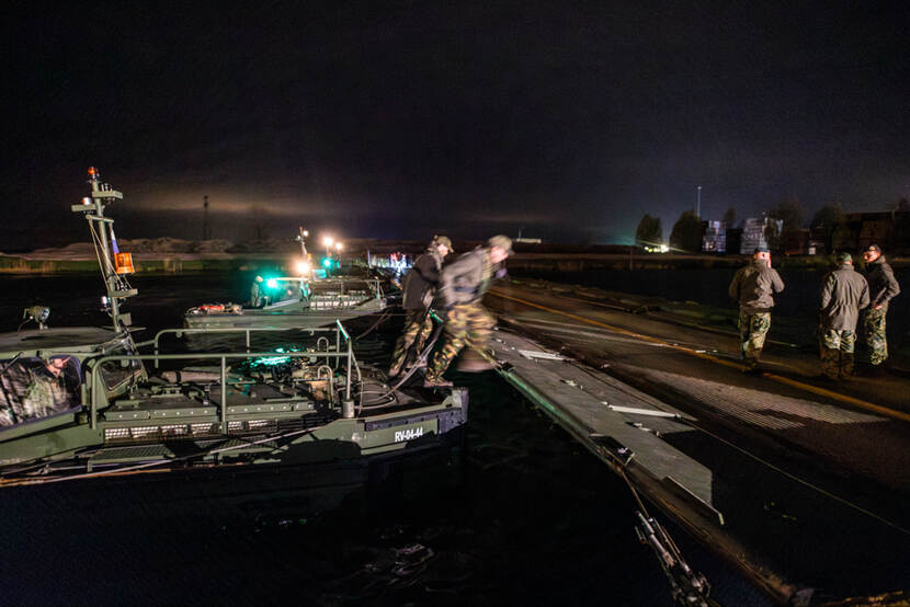 Militairen stappen vanaf een pontonbrug op het land.