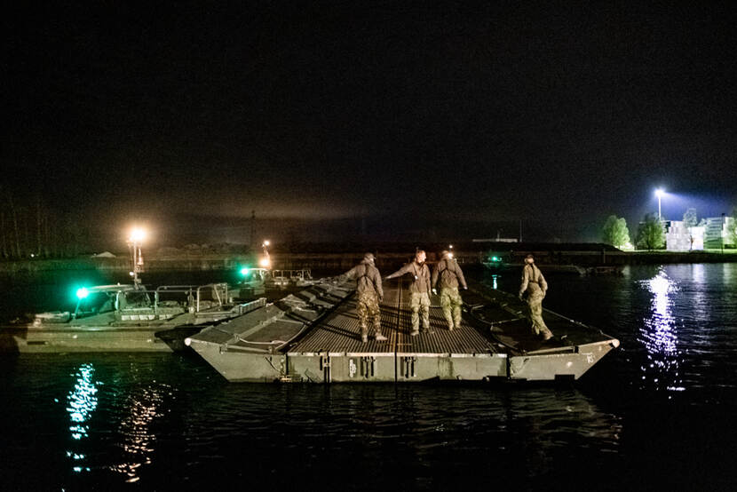 Militairen staan 's nachts op een pontonbrug in Leeuwarden.