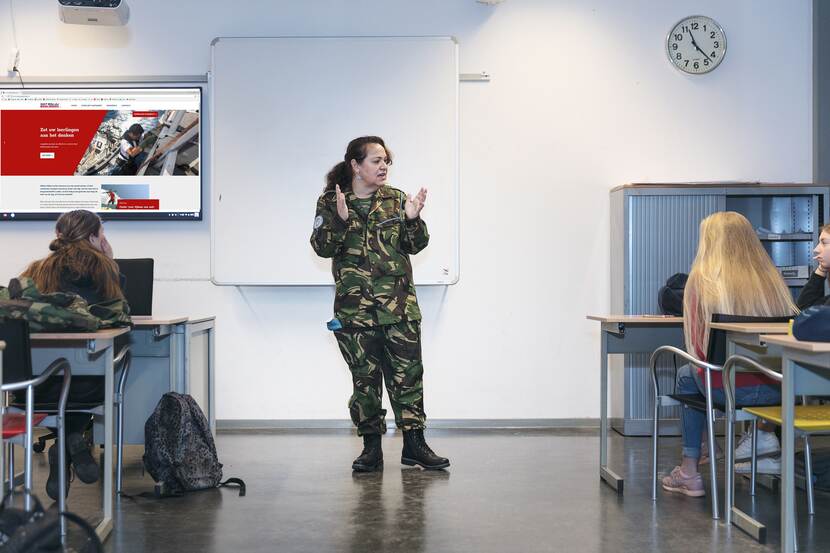 Vrouwelijke militair vertelt haar verhaal aan leerlingen in een klas.