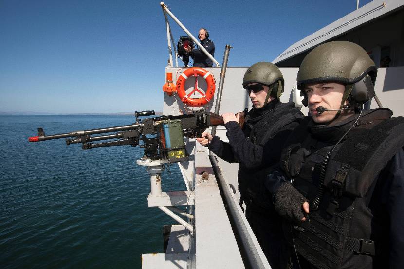 Marinepersoneel bemant een MAG-post op amfibisch transportschip Hr. Ms. Rotterdam om een gesimuleerde aanval af te slaan tijdens oefening Joint Warrior, 2013.