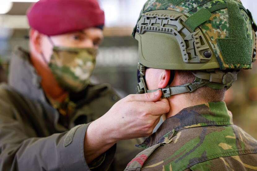 Militair help andere militair met afstellen helm.