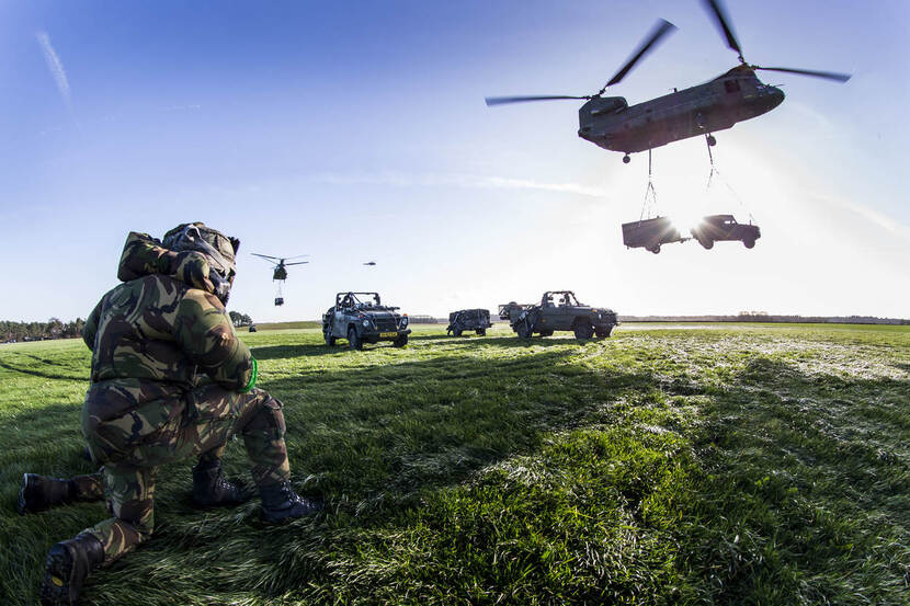 Zogenaamde riggers van 11 Luchtmobiele Brigade sluiten een slingerlading aan een Chinook en kijken hoe de helikopter wegvliegt.