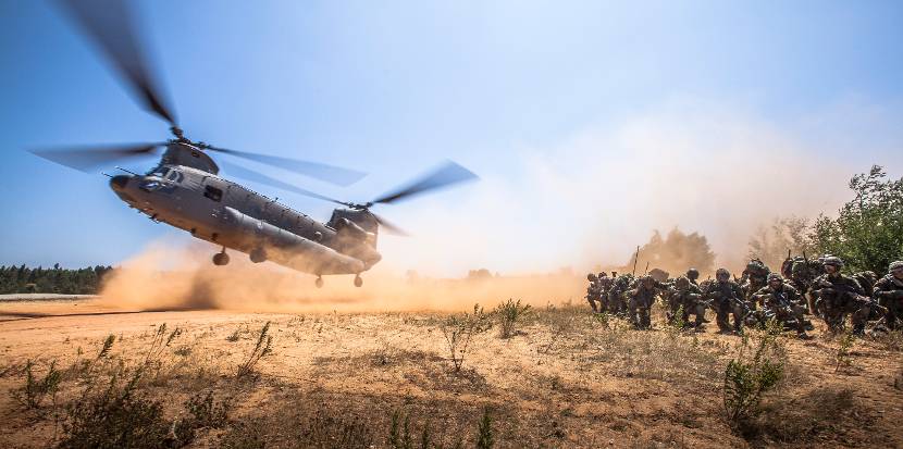 Luchtmobiele militairen groeperen zich terwijl een Chinook-transporthelikopter arriveert voor een volgende dropping.