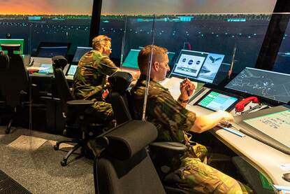 2 militairen kijken naar het beeld van de simulator luchtverkeersleiding.
