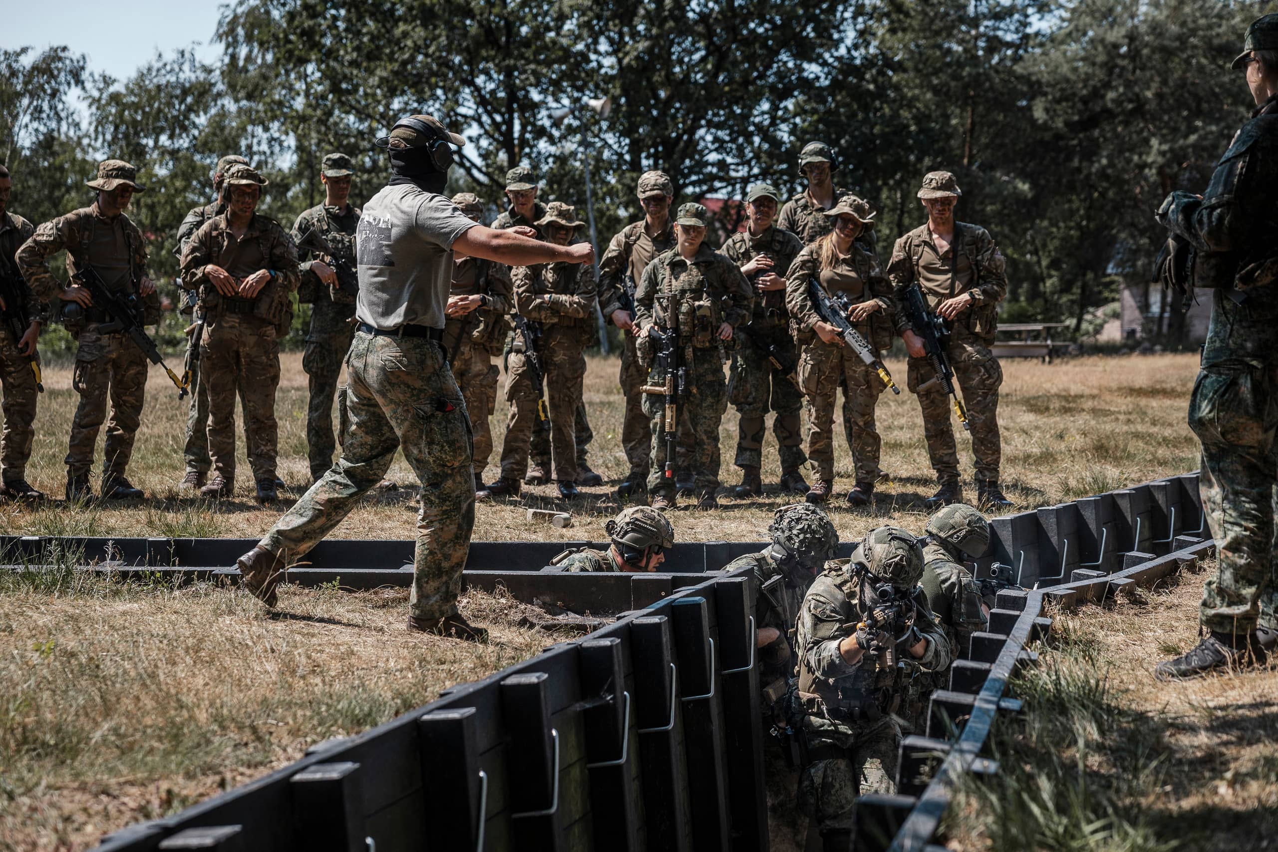 Instructeur geeft aanwijzingen aan militairen tijdens training in loopgraaf.