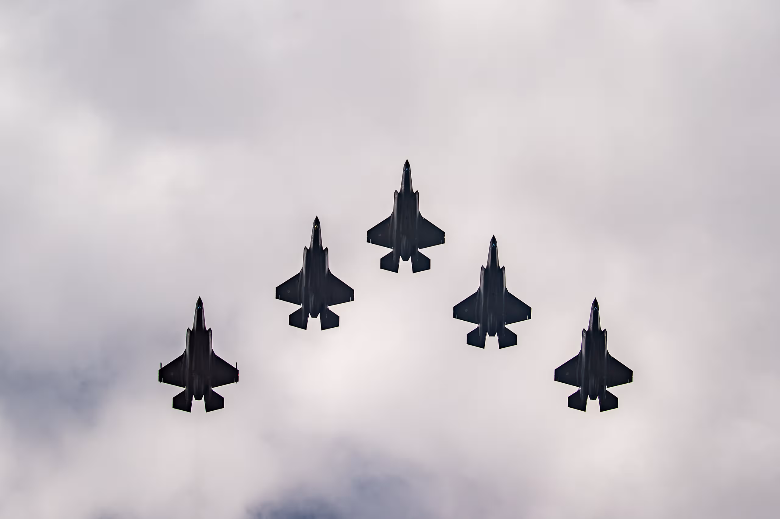 5 F-35-gevechtsvliegtuigen in V-vorm in de lucht.