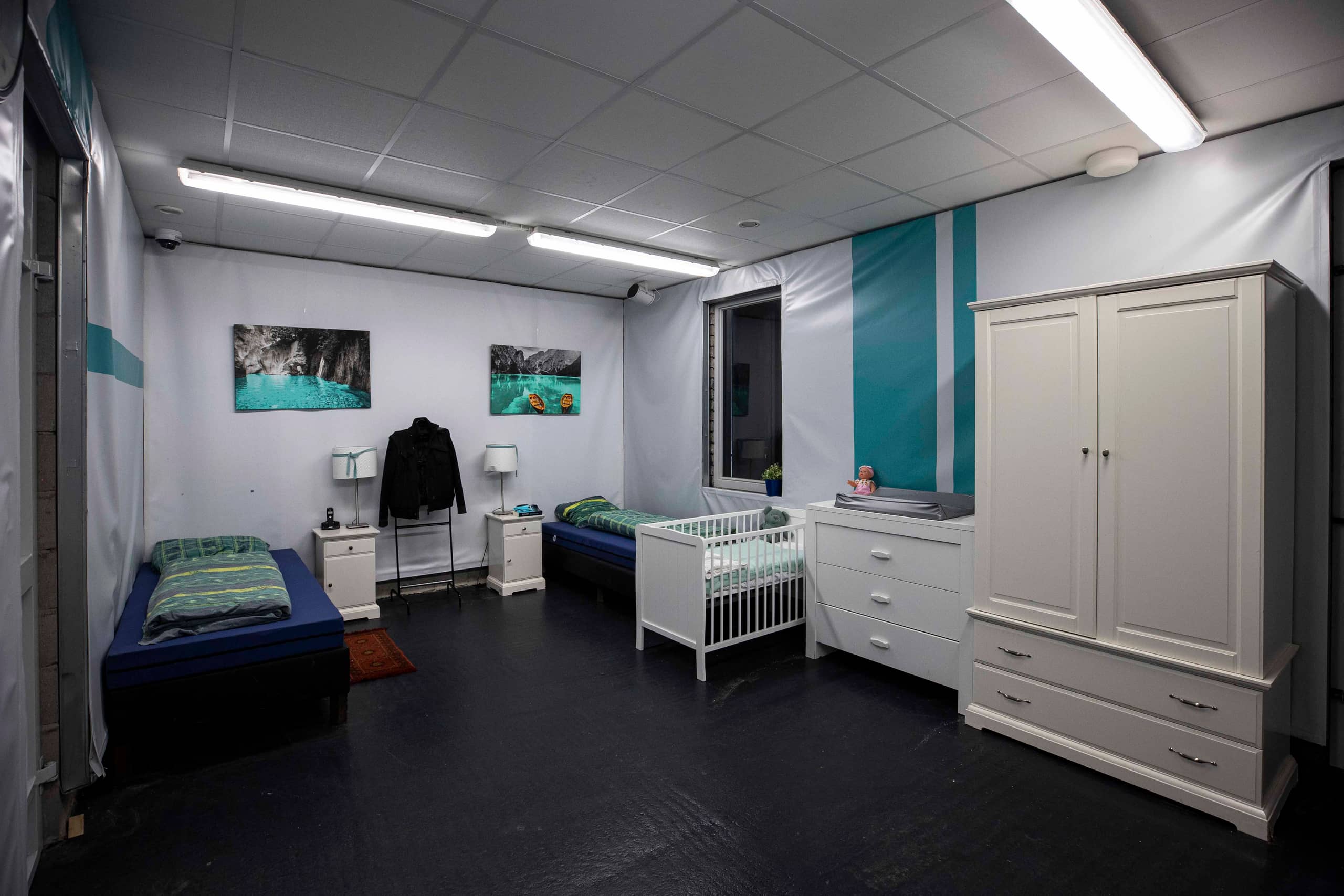 Slaapkamer met 2 bedden, een kinderbedje, nachtkastjes, lampen en een kledingkast.