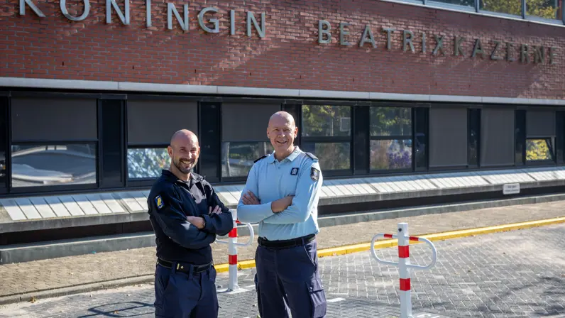 Majoor Arno en luitenant-kolonel David poseren voor de Koningin Beatrixkazerne.