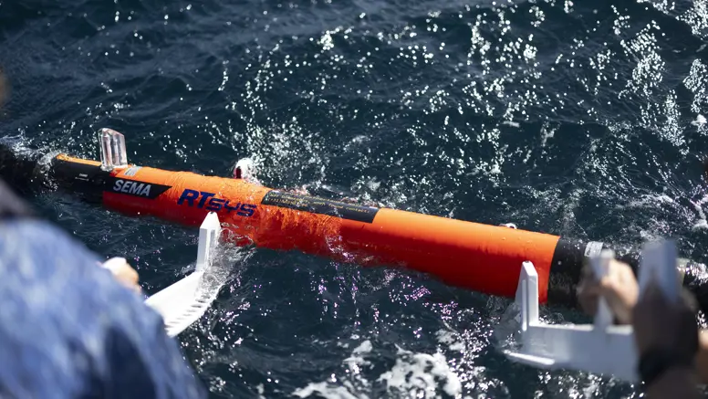  Een oranjekleurige torpedo drijft op het golvende zeewater.