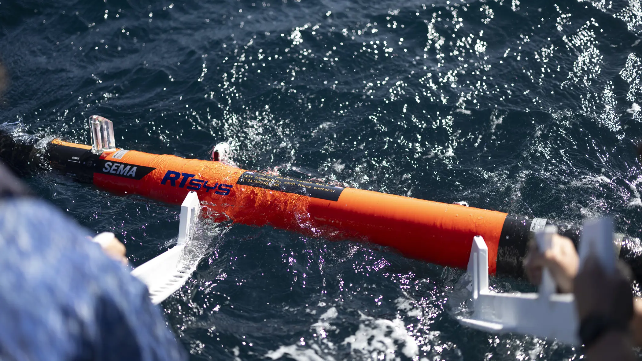  Een oranjekleurige torpedo drijft op het golvende zeewater.