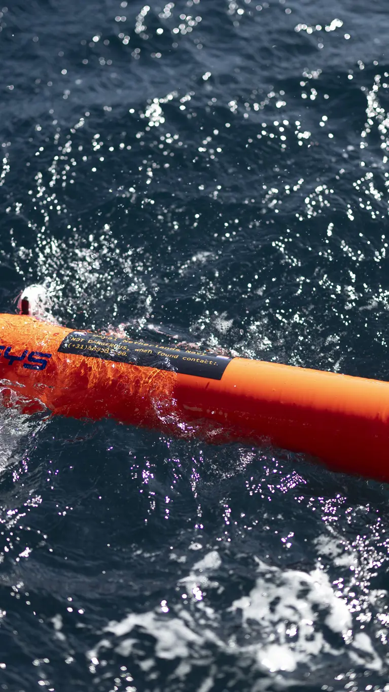  Een oranjekleurige torpedo drijft op het golvende zeewater.