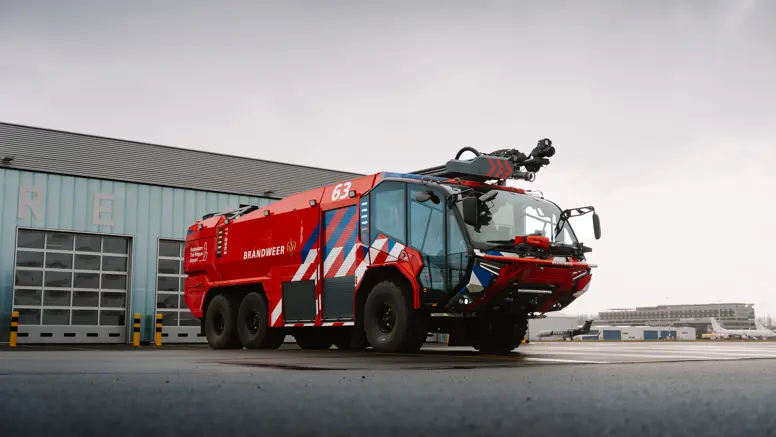 Brandweervoertuig geparkeerd op een luchthaven. 
