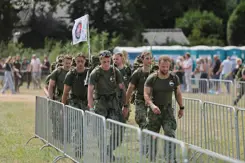 Militairen wandelen tussen dranghekken op grasveld.