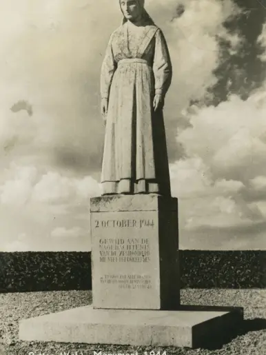 Oorlogsmonument: standbeeld van vrouw op sokkel met Nederlandse inscriptie over de zeshonderd omgekomenen, 2 oktober 1944, bomen erachter, plechtige stemming.