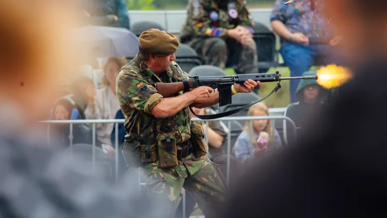 Een man in uniform en baret op schiet met een wapen.