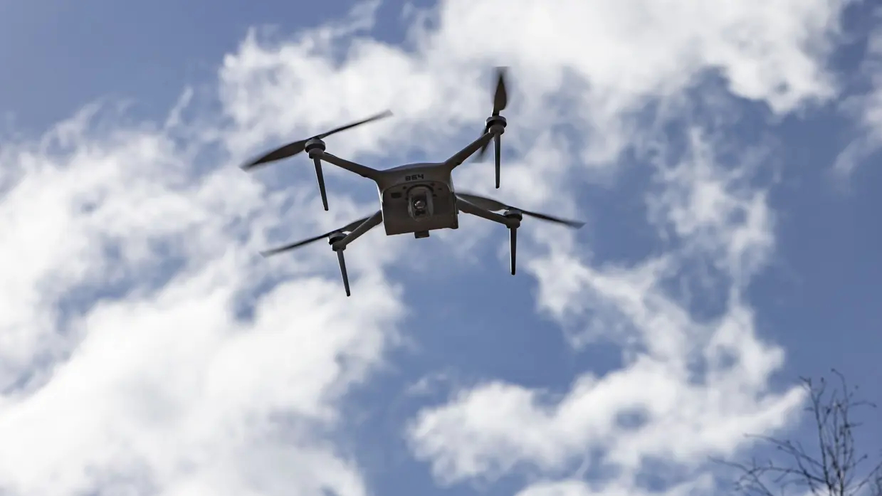 Drone in vlucht tegen een blauwe lucht met witte wolken.