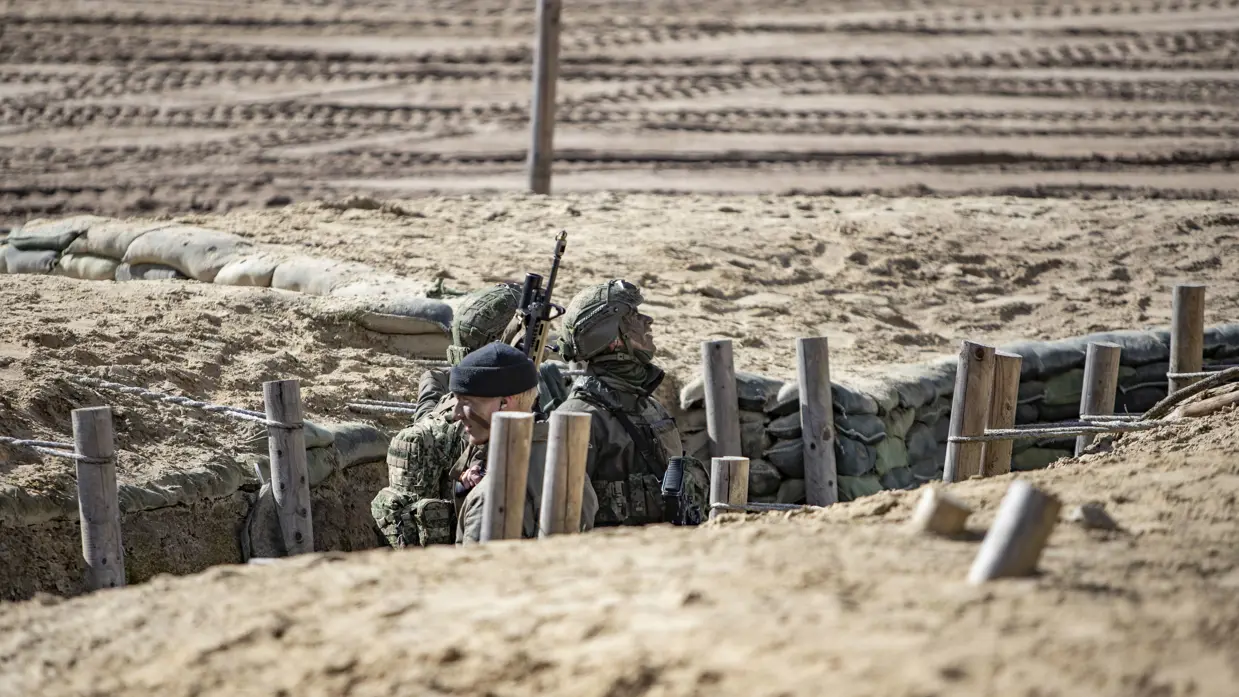 Militairen nemen positie in een loopgraaf tijdens een oefening in het veld.