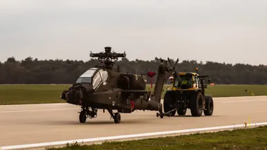 Een trekker sleept een Apache over de start- en landingsbaan.