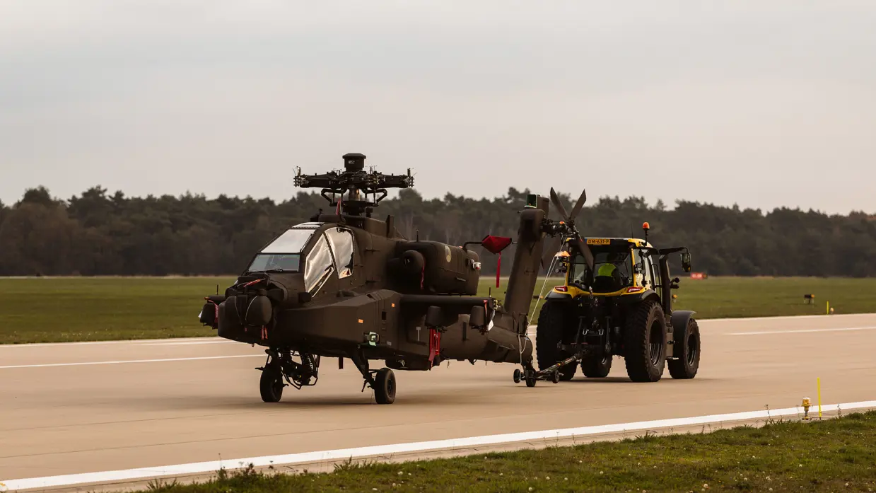 Een trekker sleept een Apache over de start- en landingsbaan.