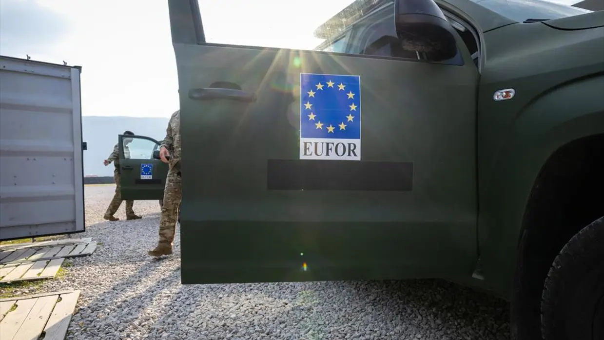 Een openstaand portier van een militair voertuig met daarop het embleem van Eufor