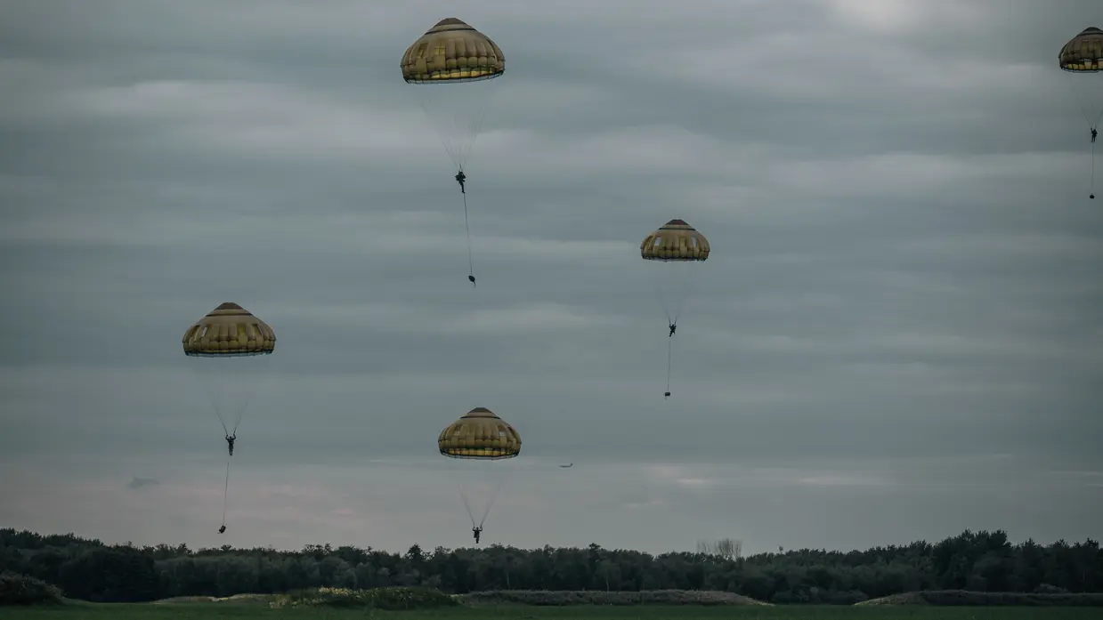 Een parachutist landt in de schemering.