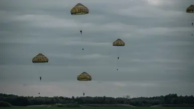 Een parachutist landt in de schemering.