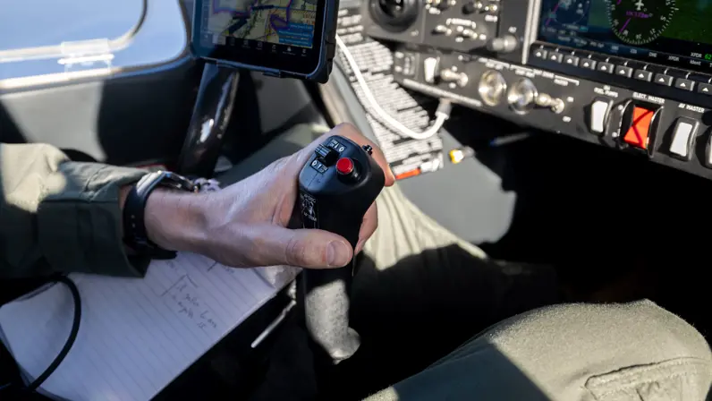 Vlieger bedient de stuurknuppel in de cockpit van het KMar-patrouillevliegtuig tijdens een vlucht. 