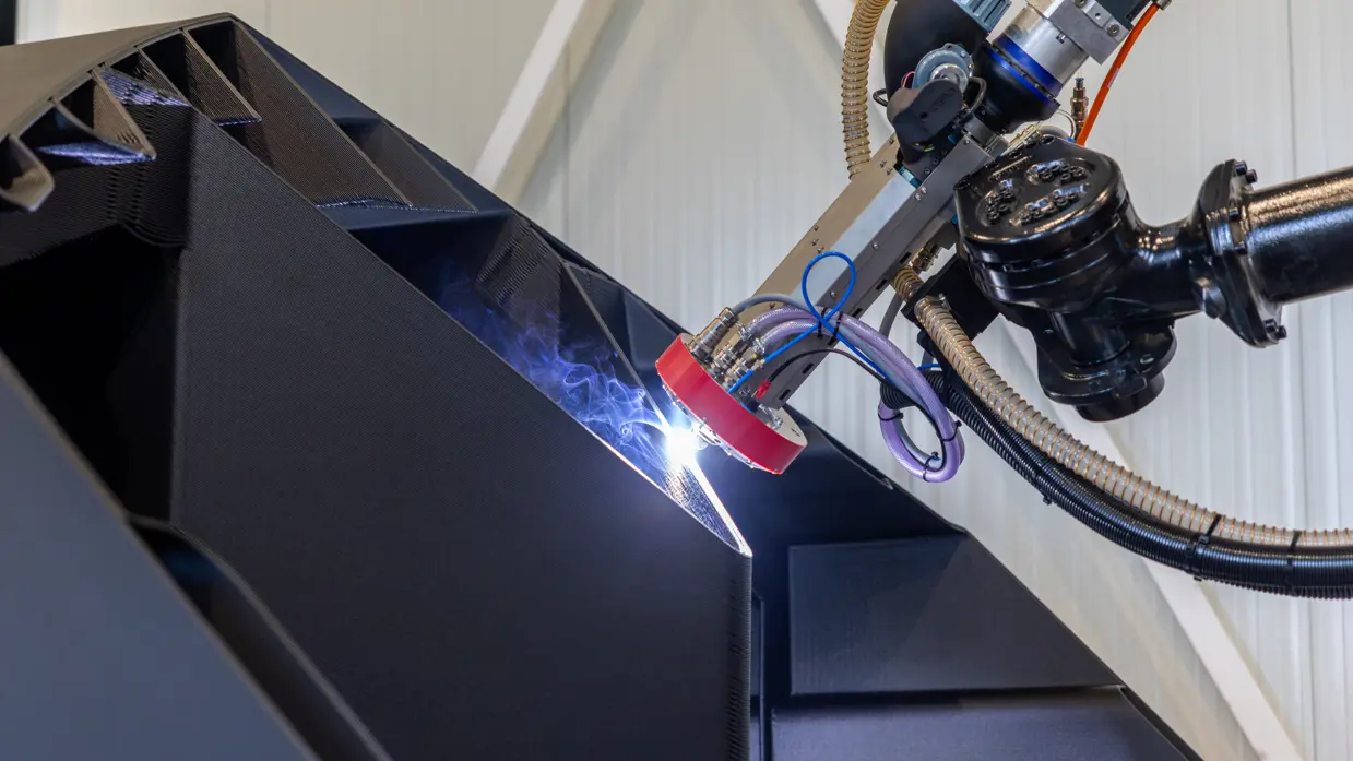 Een robot last een onderdeel van een 3D-geprinte boot.