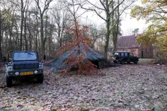 Legertent in bos met aan beide kanten een jeep.