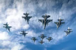 Vliegende F-16's met blauwe lucht en wolken op de achtergrond.