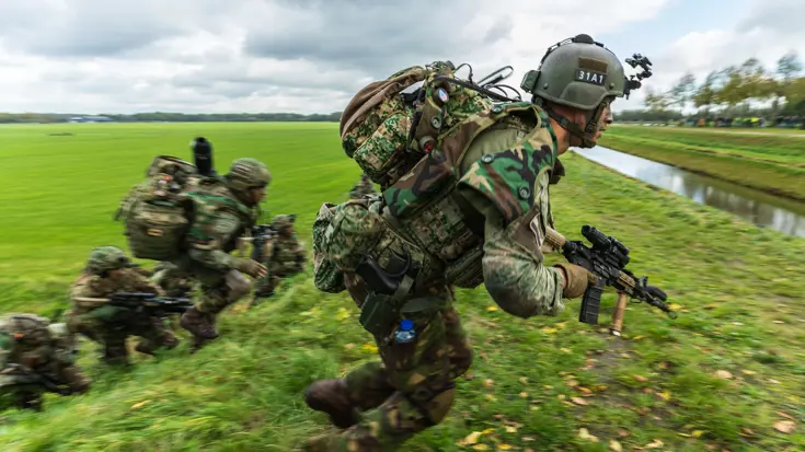 Militairen oefenen in een weiland.