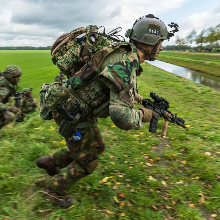Militairen oefenen in een weiland.