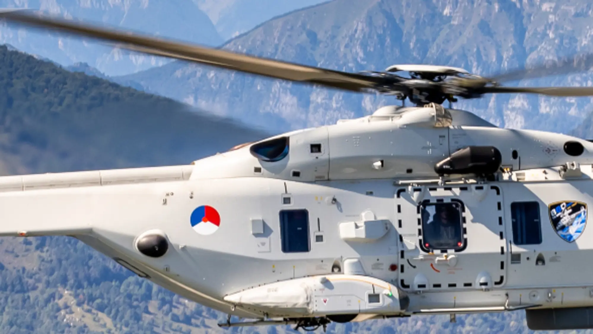 NH90-maritieme gevechtshelikopter vliegt door bergachtig terrein.