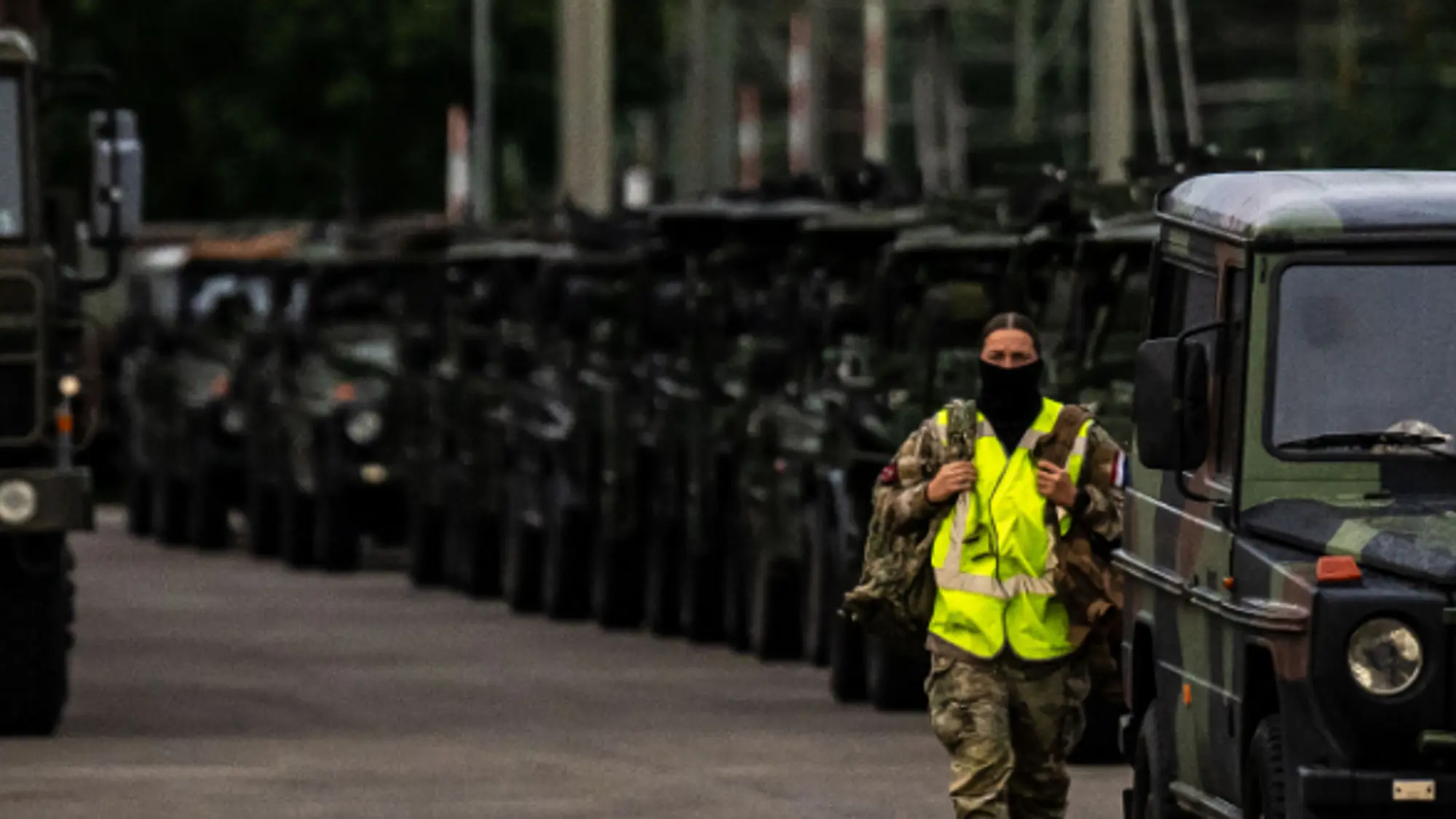 Parkeerplaats met verschillende militaire voertuigen waaronder vrachtwagens.