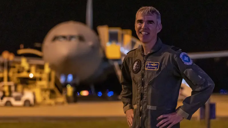 Portretfoto in avondlicht van kolonel Evert Cuppens. In de achtergrond is staat een A330 MRTT.