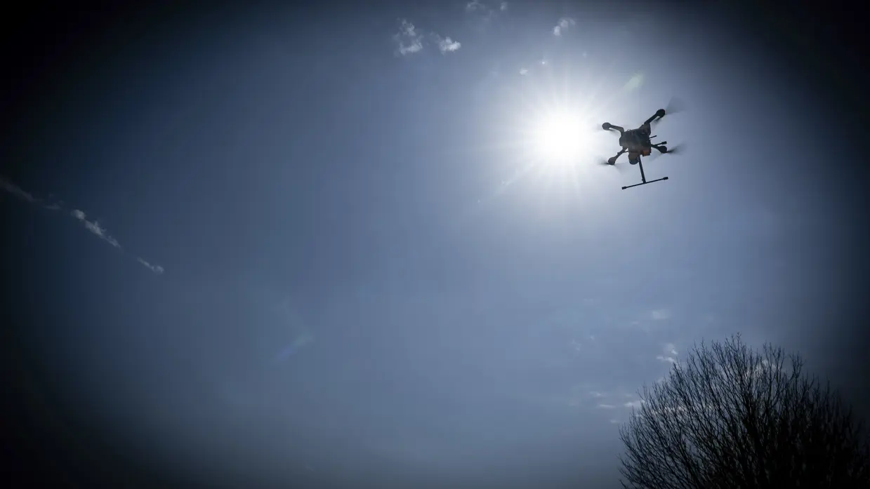 Een drone vliegt vlak voor de zon langs. De foto is bewerkt, waardoor er een zwarte rand rond het beeld is te zien.