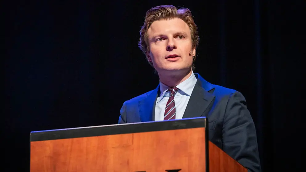 Minister Brekelmans geeft toespraak vanachter katheder.