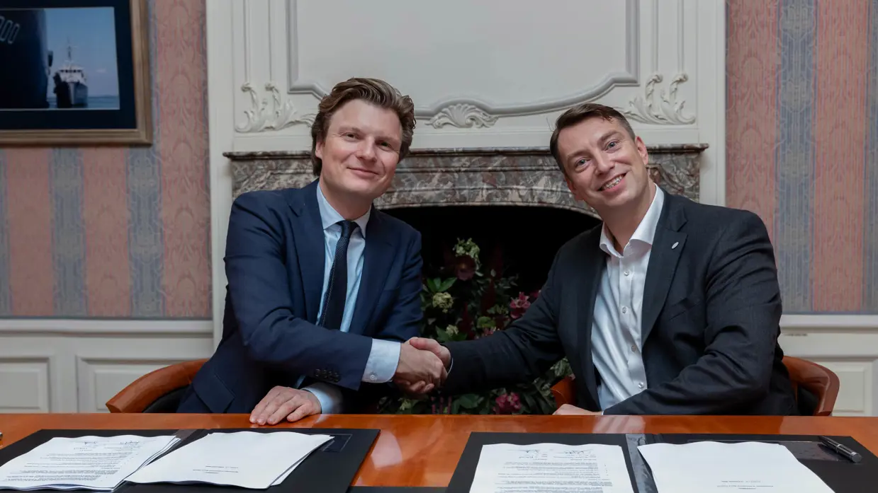 Minister Ruben Brekelmans (links) en ISISpace-CEO Jeroen Rotteveel (rechts) geven elkaar zittend achter een tafel een hand.