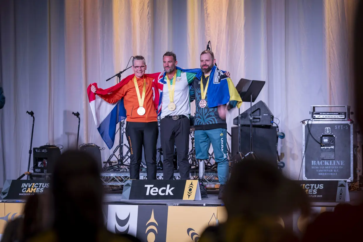 3 sporters op het podium met hun medailles.