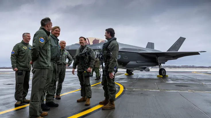 Koning Willem-Alexander praat met groep soldaten staand voor een F-35.
