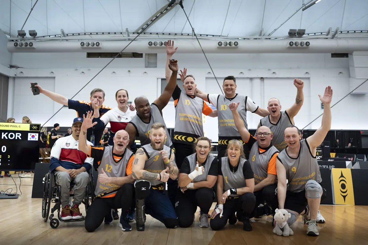 Een groep Nederlandse sporters poseren juichend voor de foto.