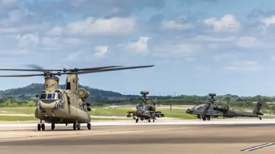 Een Chinook met daarachter twee Apaches taxiënd op de startbaan.