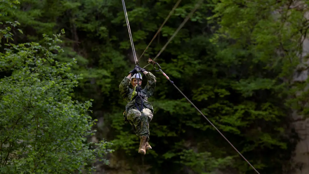 Militair daalt tussen de bomen af met een zipline.