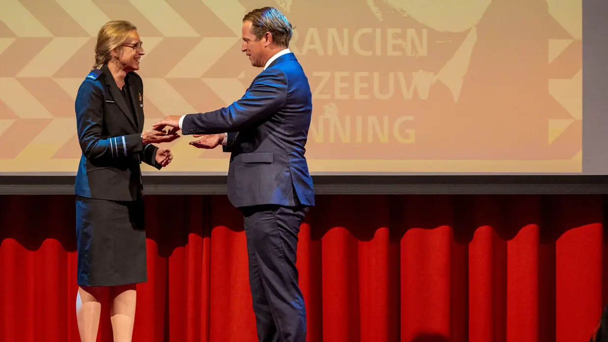  Boekholt-O’Sullivan staat op een podium en krijgt de prijs uit handen van voormalig staatssecretaris Gijs Tuinman.