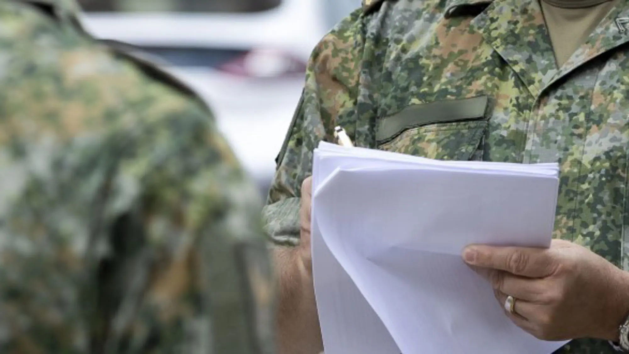 Close-up van hand van militair die papieren vasthoudt.