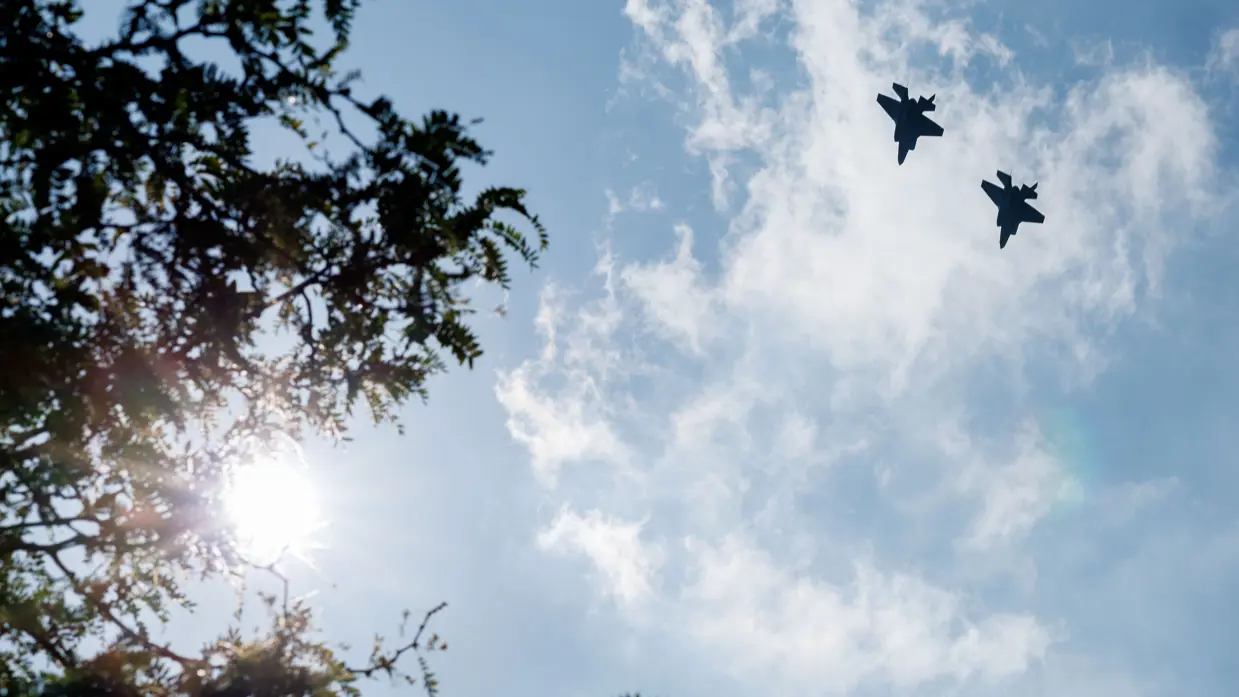 twee f-35’s draaien naar rechts weg, links staan bomen.