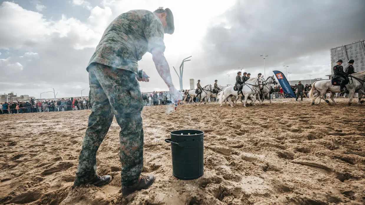 Militair op het strand steekt een rookpot aan.